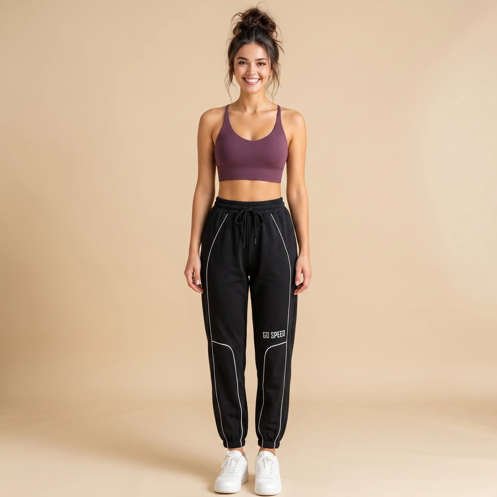 Woman in black high-waist loose-fit joggers with white side piping, tapered cuffed sweatpants, front view